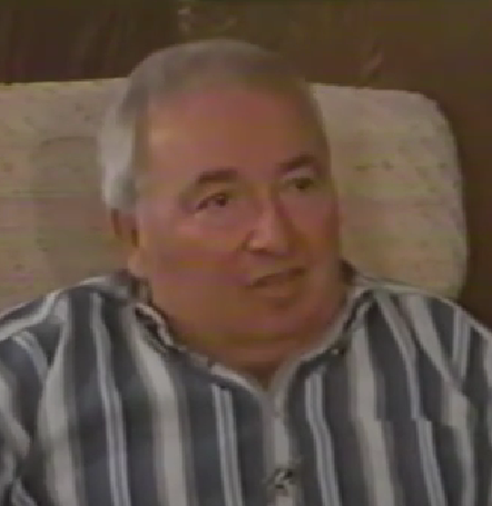 Jack Dygola, a Holocaust survivor, speaks during a recorded interview. He has short gray hair and wears a black and white striped shirt.