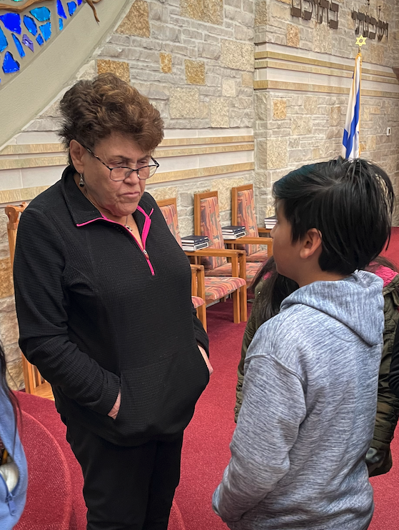 Edie Pump, a Holocaust survivor and HERC Speakers Bureau speaker, listens attentively as a middle-school-aged student asks her a question during a school visit program at a local synagogue.