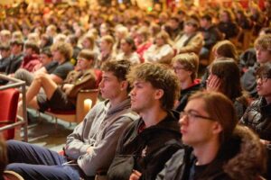 Students seated in an auditorium listen attentively during a HERC Holocaust education program."