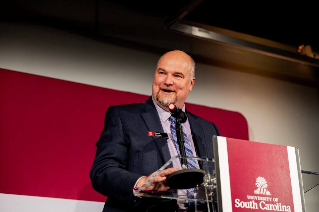 Dr. Doyle Stevick addresses an audience at a podium during the Navigating Summer workshop.