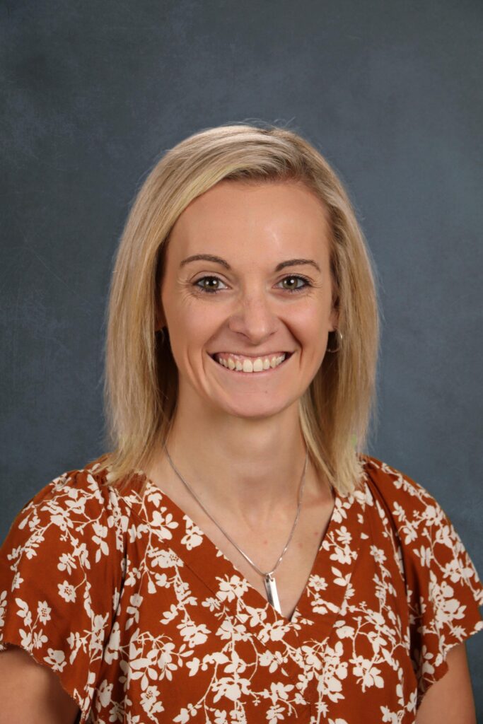 Woman with shoulder length blond in red shirt smiles 